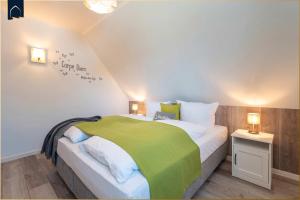 a bedroom with a large bed with a green blanket at Ferienhaus Glück unter Reet in Zirchow