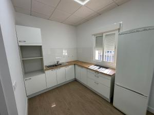an empty kitchen with white cabinets and a window at Casa ARANAL in Málaga