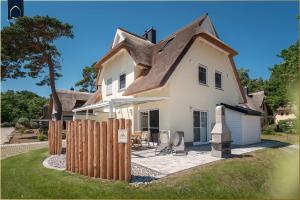 a white house with a brown roof at Ferienhaus Glück unter Reet in Zirchow
