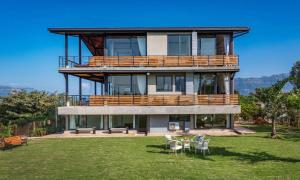 uma grande casa com uma varanda e um relvado em SaffronStays Satori Perch Regal - 4BR Tuscan-style villa with pool, farm meals & 270 Degree Mulshi Lake views near Pune em Mulshi