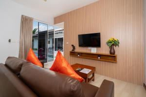 a living room with a brown leather couch and a tv at Phuket La Siesta Pool Villas & Pool Access Rooms in Nai Harn Beach