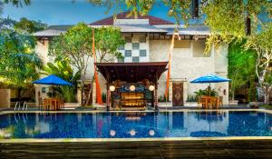 a house with a swimming pool in front of a house at Best Western Kuta Villa in Kuta