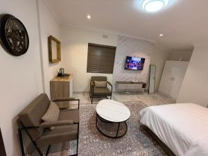 a bedroom with a bed and a couch and a tv at The Benjamin Guest House in Edenvale +29 photos