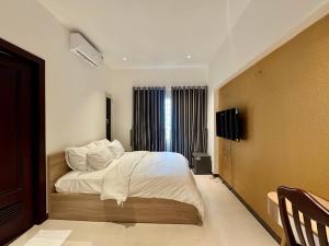 a bedroom with a bed with white sheets and pillows at Amazing Merit Trung Son in Ho Chi Minh City