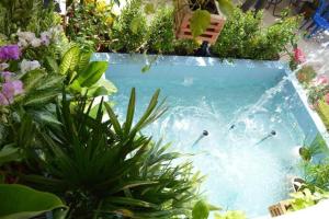 a pool in a garden with people swimming in it at Nan Treasure Hotel in Ban Hua Wiang Nua