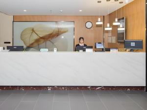 a woman standing behind a large white counter in an office at Green Tree Inn Tianjin Jinnan Linshijun University of Finance and Economics in Tianjin