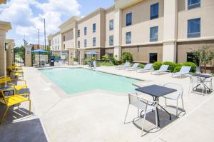 einen Pool mit Tischen und Stühlen vor einem Gebäude in der Unterkunft Hampton Inn West Monroe in West Monroe