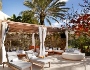 Hilton West Palm Beach في ويست بالم بيتش: فناء فيه كنب وكراسي وتلفزيون