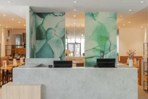 een lobby met een receptie met een groene muur bij Wyndham Garden Munich Messe in München