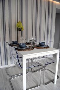 a white table with chairs and wine glasses on it at Apartament 1Maja in Koszalin