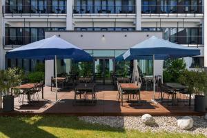a patio with tables and chairs under blue umbrellas at Wyndham Garden Munich Messe in Munich