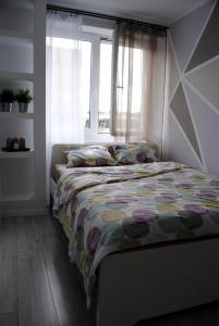 a bedroom with a bed with a quilt and a window at Apartament 1Maja in Koszalin