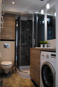 a bathroom with a shower and a washing machine at Apartament 1Maja in Koszalin