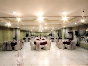 une salle de banquet avec des tables blanches et des chaises blanches dans l'établissement Hotel Veniz, à Baguio