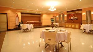 une salle à manger avec des tables blanches et des chaises blanches dans l'établissement Patria Palace Hotel, à Blitar