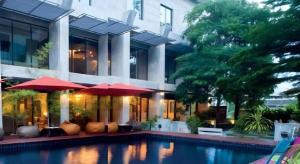 a house with a swimming pool with red umbrellas at Klim Hotel in Buriram
