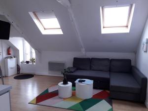 Una sala de estar con un sofá y dos ventanas. en Un nid douillet sous les toits, en Cancale