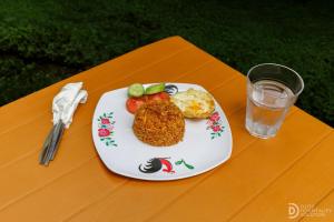 Un plato de comida en una mesa con un vaso de agua. en SG Hotel Pangandaran, en Pangandaran 11 fotos más