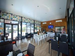 a restaurant with white tables and chairs and windows at GT Residence Hotel in Ban Yang