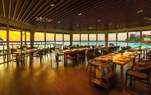 a restaurant with tables and chairs and a pool at Bangsaen Villa Hotel in Ban Laem Thaen