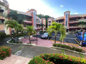 a parking lot with palm trees in front of a building at 1DR Charming 3-Bedroom Retreat Santo Domingo in Santo Domingo