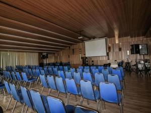 a lecture hall with blue chairs and a white screen at Hotel 61 Medan in Medan