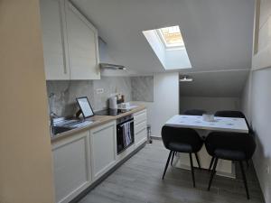 a kitchen with white cabinets and a table and chairs at Studio Apartmani in Rijeka