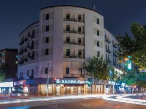 a large white building on a city street at night at Magnotel Shanghai Henglong Plaza in Shanghai