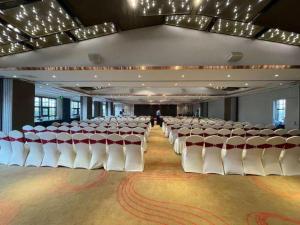 a large room with rows of white chairs in it at Hangzhou Cosy Park Hotel in Hangzhou