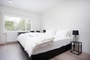 a white bedroom with a large bed and a window at Nordurey Hotel City Garden in Reykjavík