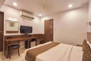 a bedroom with a bed and a desk with a television at The Sapphire Hotel in Nagpur