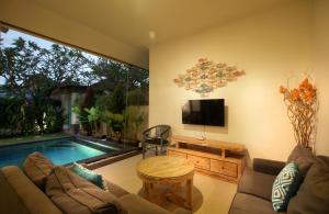 a living room with a couch and a tv and a pool at Villa Lotus Flower Sanur in Sanur