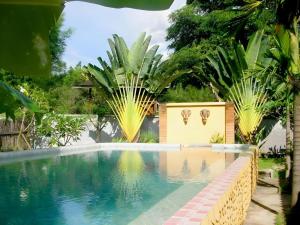 a swimming pool in a backyard with palm trees at Aroma Pai Spa Hotel in Ban Tha Pai