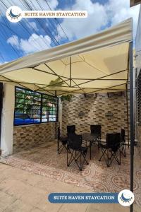 a patio tent with chairs and a table under it at Suite Haven Staycation in Sampong