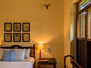 a bedroom with a bed and a table with a lamp at Saranyam by LuxUnlock Private Villas in Kāraikkudi +48 photos