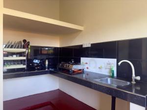 a kitchen with black counter tops and a sink at Viska Villa 2 Bedroom Home 5 min to Hiriketiya in Nilwella +13 photos
