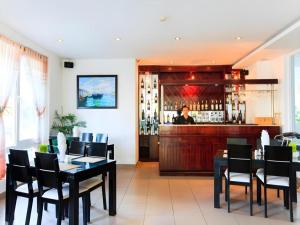 a restaurant with a bar with a person behind the counter at Paragon Villa Hotel Nha Trang in Nha Trang