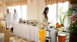 une femme debout dans une cuisine avec deux chefs dans l'établissement New Moon Hotel, à Hanoï