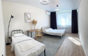ein Zimmer mit zwei Betten und einem Tisch und einem Schreibtisch in der Unterkunft Новая квартира со всеми условиями Сити центре in Oral