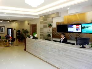 a woman sitting at a counter in a lobby at GreenTree Inn Langfang GuAn County Xinyuan Street Express Hotel in Gu'an