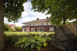 ein großes Backsteinhaus mit einem Baum und einem Felsen in der Unterkunft Villa het Bascour in Vierlingsbeek