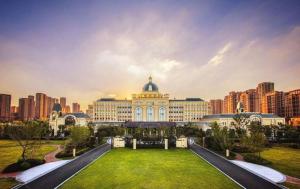 a large building with a lawn in front of a city at The Qube Hotel Nanchang East in Nanchang