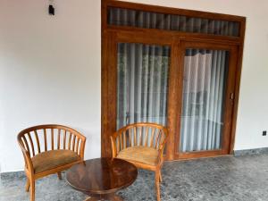 two chairs and a table and a glass door at Cashew Garden Resort & Restaurant in Dambulla