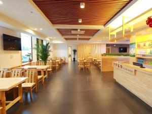 un restaurant avec des tables et des chaises en bois dans l'établissement GreenTree Inn Yichun Qingshan Street Express Hotel, à Jiamusi