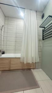 ein Bad mit einer Dusche mit einem weißen Duschvorhang in der Unterkunft Новая квартира со всеми условиями Сити центре in Oral + 12 Fotos