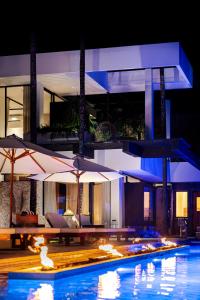 een zwembad met parasols voor een gebouw bij Villa Zeno Arete Pererenan 6 Bedroom , Ice Bath, Sauna and Gym in Tumbak Bayuh