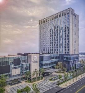 The QUBE Hotel Jingzhou في Caoshi: مبنى زجاجي كبير أمام شارع