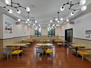 une salle à manger avec des tables, des chaises et des lumières dans l'établissement GreenTree Inn Ganzhou Gan County Bus Station, à Meilin