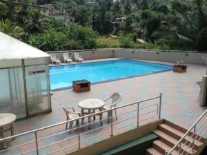 a swimming pool with chairs and a table on a balcony at Devon Hotel in Kandy