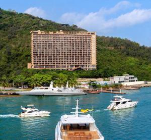 a group of boats in the water in front of a large building at Grand Metro Park Bay Hotel in Sanya